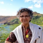 Woman smiling outdoors by a scenic landscape.