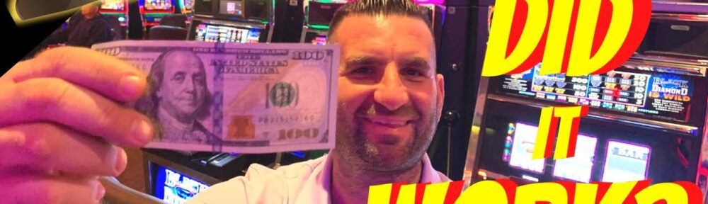 Man holding money in front of slot machines.